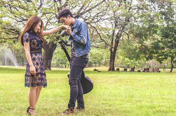 beautiful young couple standing kiss on the park with a guitar.