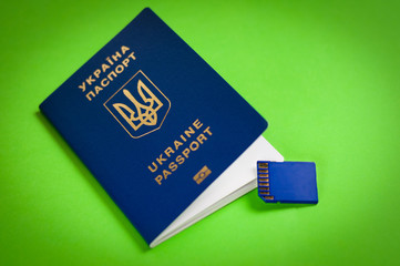 One blue biometric ukrainian foreign passport with gold color inscription and coat of arms on green background near plastic memory card. Visa-free travel concept