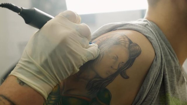Tattoo artist makes a tattoo on a man's body