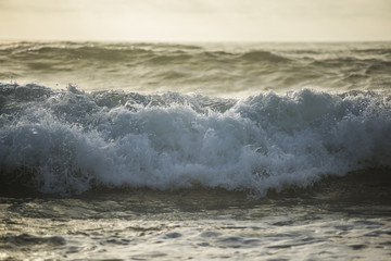Foamy stormy wave crashing during sunset presenting a dark mood