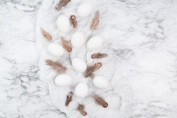 white eggs and brown feathers on a marble counter top
