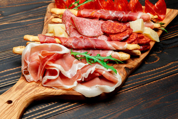 Cold smoked meat plate with pork chops, prosciutto, salami and bread sticks