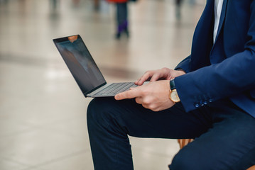 A businesswoman working on a laptop sitting on a bench, close up. Forex cryptocurrency trading, business concept.