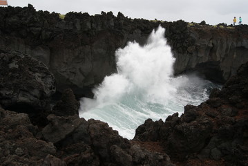 Tourists walking in a cliff with a strong sea in Azores islands