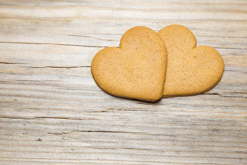 Two heart shaped gingerbread cookies on wooden background.
