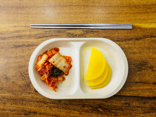 Traditional Korean fermented food kimchi and radish with chopsticks.