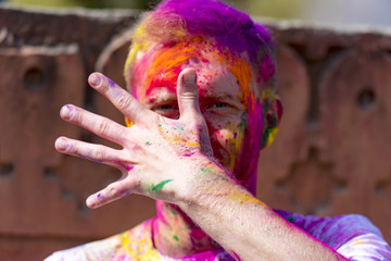 Cheerful man in colored t-shirt during Color Holi festival	