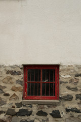 Square red wooden window in a stone and whitewashed wall