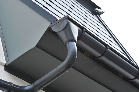 Dachrinne aus beschichtetem Metall . Dach mit beschichteten Aluminiumschindeln gedeckt