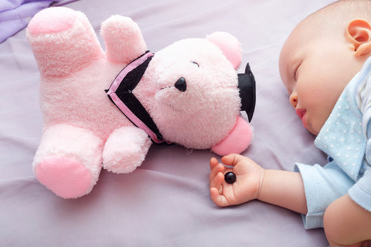 Teddy bear's eye was detached by toddler and in sleeping 10 months old baby hand, beware of choking hazard for children concept