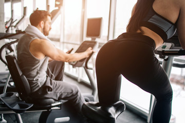 A picture from another angle where girl's back is seen. Also there is her boyfriend working hard on the exercise bike as well.