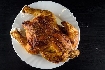 fried chicken whole, on a white plate on a wooden background