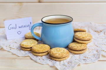 blue mug of tea and oatmeal cookies on wooden background