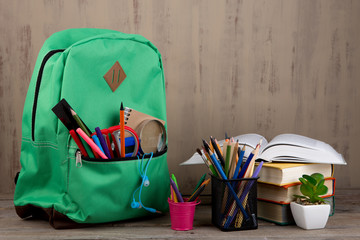 Education concept - school backpack with books and other supplies on the desk