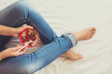 Healthy eating concept. Women's hands holding bowl with muesli and frozen berries. Top view. Lifestyle photo. Toned image. Toned