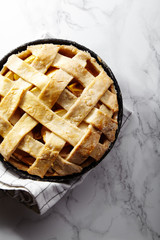 Pie crust design ideas - various ways of pie decoration with lattice and leaves. Apple, strawberry and raspberry pies cooked and served with tea on white marble table
