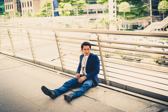 businessman unemployed from company sitting on street, he is feeling of stressed and sadness, concept of business failure and unemployment problem.
