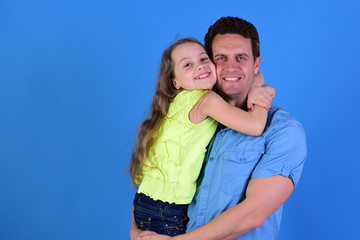 Childhood and family concept. Schoolgirl sits on dads arms.