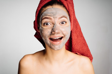 the happy woman after the shower applies a cleansing mask on her face