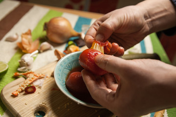 Men's hand peeling canned tomatoes from skin.