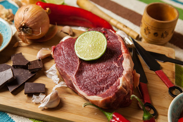 Beef with chocolate, lime, garlic and onion on cutting board.
