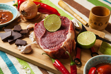 Beef with chocolate, lime, garlic and onion on cutting board.