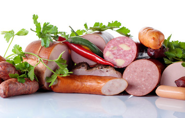 Different sausages and smoked meats isolated on white .