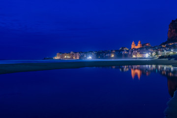 Naklejka premium Il pittoresco borgo marinaro di Cefalù riflesso sull'acqua di notte, Sicilia 