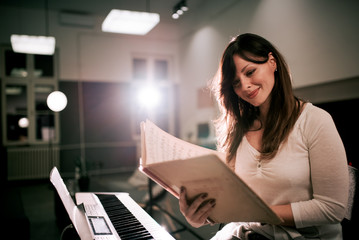 Obraz premium Smiling woman reading music sheet.
