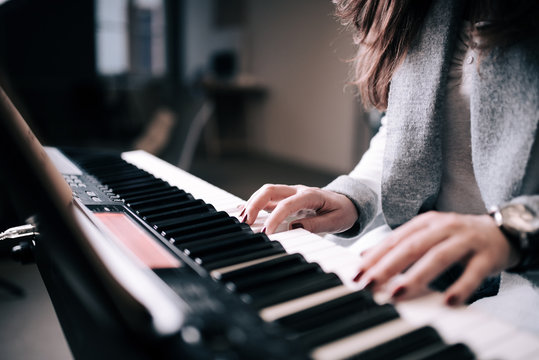 Close-up image of unrecognizable female person playing piano.