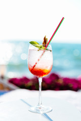 Summertime. Close-up view of cocktail with mint in wineglass, against the sea background. Leisure concept.