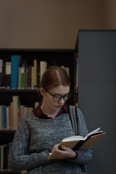 Young woman reading a book in library