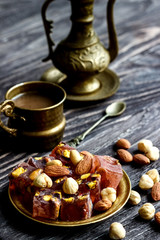Oriental Arabian sweets with different nuts a cup of coffee. Eastern sweets. Traditional Turkish delight (Rahat lokum) on a wooden background. View from above.