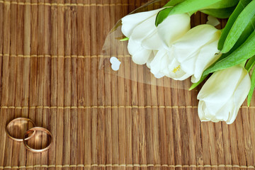 A bouquet of white tulips and wedding rings.