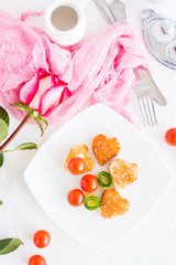 Toasts in the form of heart, cherry and cucumber on a plate. Dish served for lovers and rose. Top view