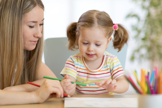 Mother and her daughter are drawing at table