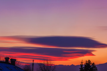 Obraz premium a spectacular cloudscape in the mountains /the refraction of sunlight colored the orange and purple sky at sunset