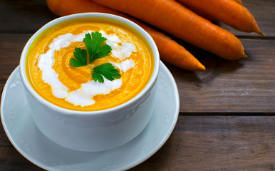 Carrot cream-soup with fresh carrots  on wooden table