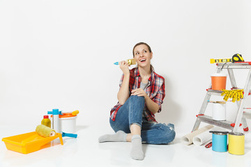 Pretty woman in casual clothes sitting on floor with brush, instruments for renovation apartment room isolated on white background. Wallpaper accessories for gluing painting tools. Repair home concept