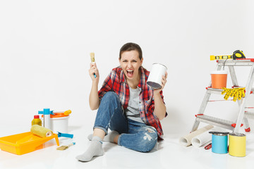 Screaming mad woman sitting with brush, paint can, instruments for renovation apartment isolated on...