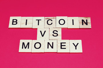 Wooden blocks on a red background spelling words Bitcoin vs money