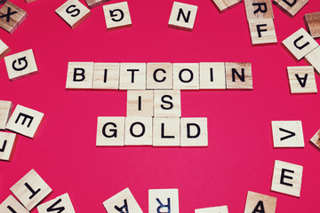 Wooden blocks on a red background spelling words Bitcoin is Gold
