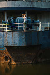 Young beautiful mixed race woman stands on an abandoned giant ship.