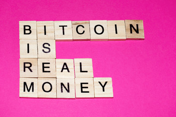 Wooden blocks on a pink background spelling words Bitcoin Is Real Money