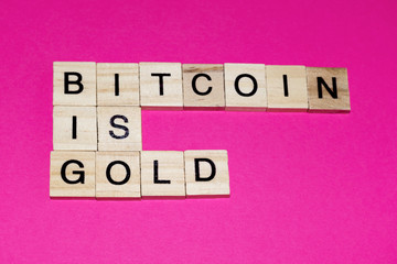 Wooden blocks on a pink background spelling words Bitcoin Is Gold