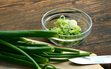 Spring onion with wooden board on wooden background