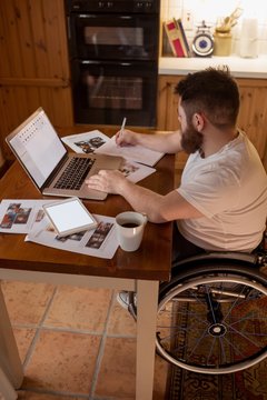 Disabled man noting while using laptop