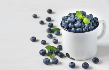 Heidelbeeren / Blaubeeren mit Minze dekoriert, in einer Tasse, frisch nach der Ernte