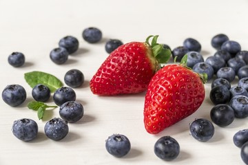 Blaubeeren und Erdbeeren auf weißem Holzhintergrund