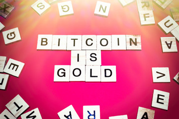 Wooden blocks on a red background spelling words Bitcoin Is Gold